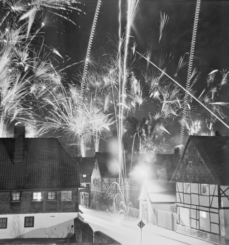 Das s/w-Foto zeigt Feuerwerk über Häusern, sehr viel Feuerwerk.