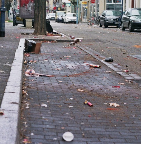 Das Bild zeigt einen Parkstreifen an einer Einbahnstraße, überall liegt Müll vom Feuerwerk