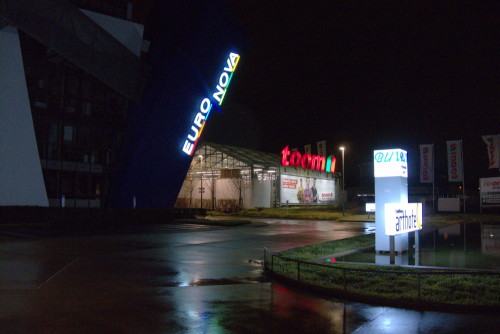 Das Bild zeigt eine Einfahrt, man sieht Leuchtreklame Euro-Nova, Arthotel und toom Baumarkt.