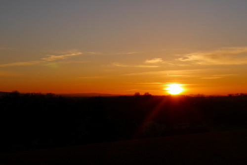 Das Bild zeigt einen Sonnenuntergang, die Sonne berührt gerade die Erde