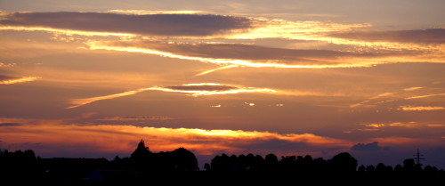 Das Bild zeigt Wolken, die von der Sonne von "Hinten" angestrahlt werden und blau/orange Leuchten