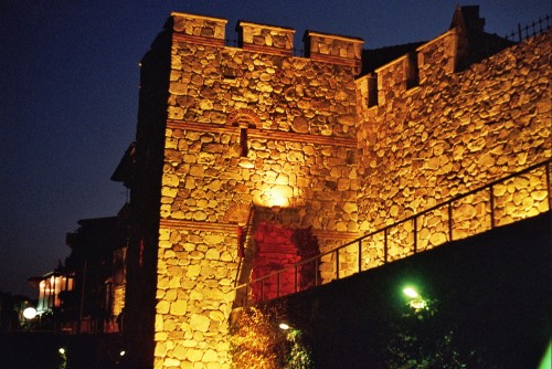 Das Foto zeigt die gelb und grün ausgeleuchtete Stadtmauer von Sozopol und den Fußgängerweg an der Mauer