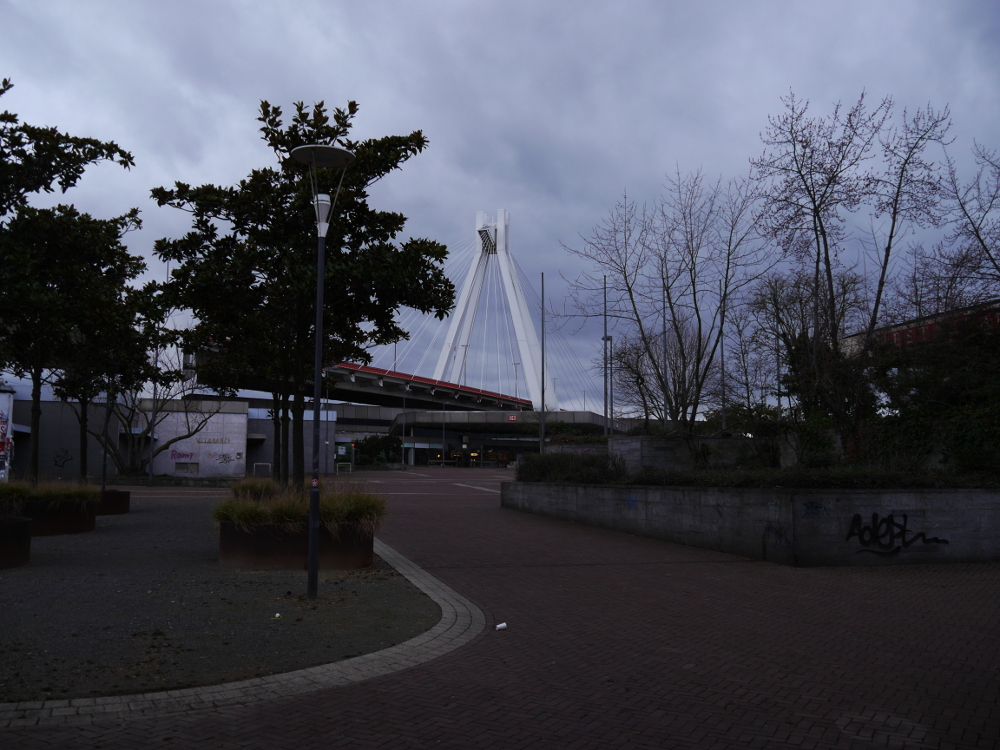 Das Foto zeigt den Hauptbahnhof von Ludwigshafen, ein graues Betongebäude. Über dem Bahnhof ist eine Autobahnbrücke.