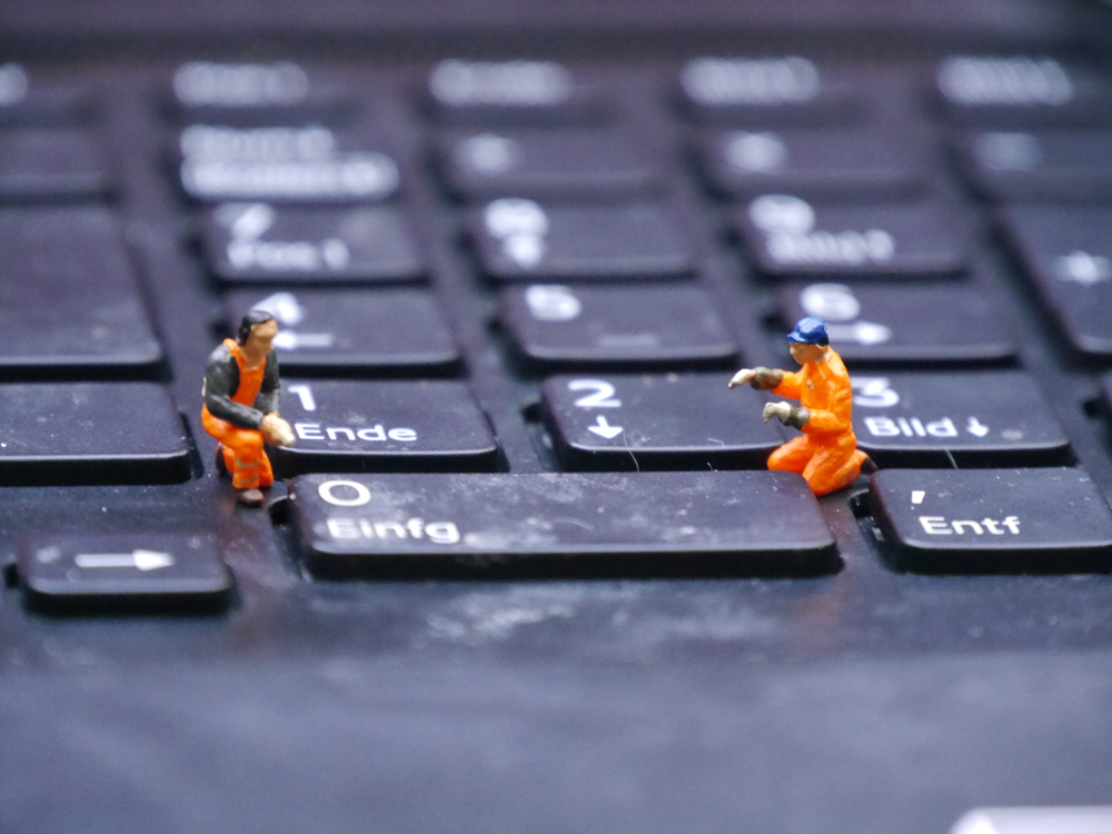 Dasa Foto zeigt Modell-Bauarbeiter in Warnkleidung, die auf der Tastatur eines Computers "arbeiten".