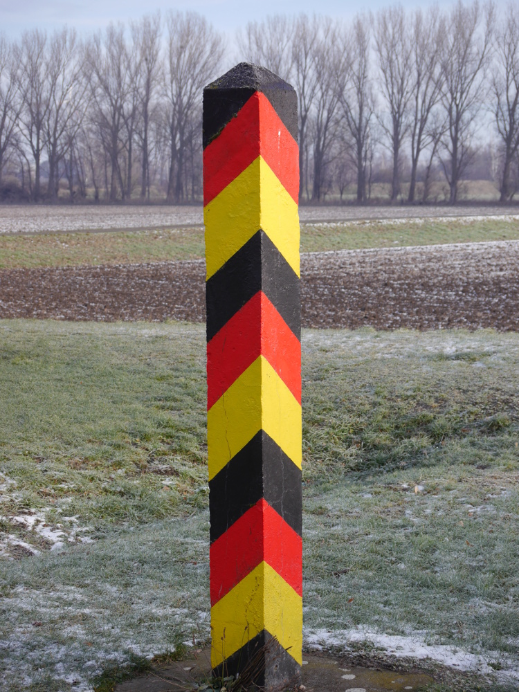 Ein Betonpfoster, der schwarz-rot-gold gestrichen ist. Diese Pfosten waren fürher die Grenzpfosten der DDR