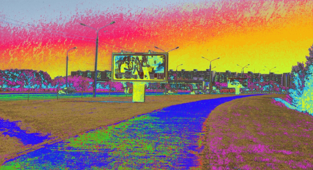 Ds Foto zeigt die skuril-abstrak verfärbte Straßenszene in der Stadt Minsk, man kann große Werbeplakate zwischen dem Fußweg und der breiten Autostraße erkennen, im Hintergrund sind Plattenbauten. Die Farbgebung ist extreum unnatürlich.