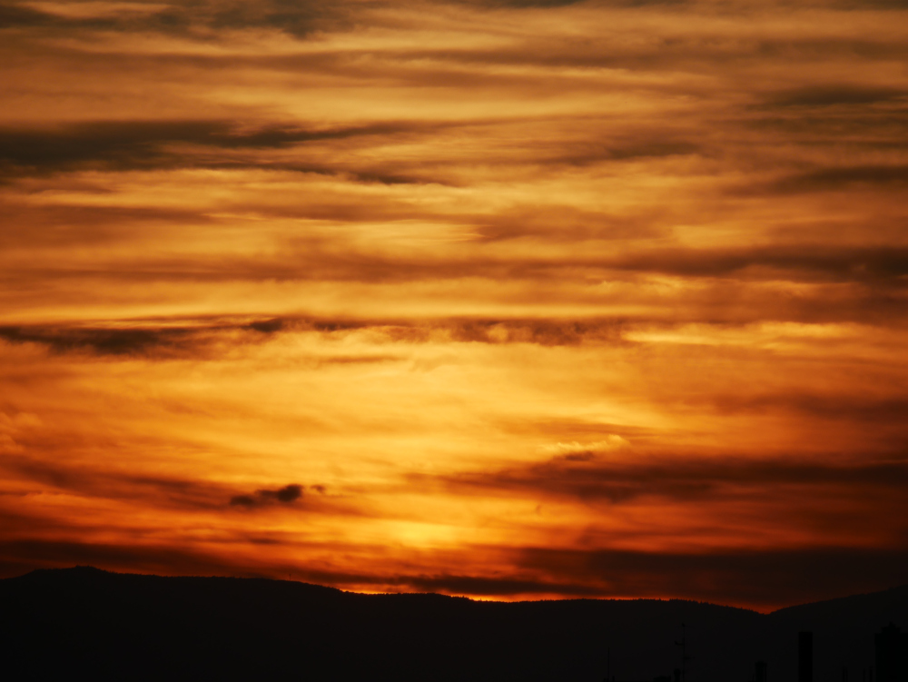 Das Fot ist schwer zu beschreiben, es zeigt eine Vielzahl von orang-gelbenen Wolkenschichten im Sonnenuntergang, die Farben laufen inneinander über und manches wirkt auch ein wenig unscharf.