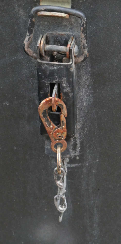 Detailaufnahme eines Verschlusses mit einer Kette und einem verrosteten Hacken.