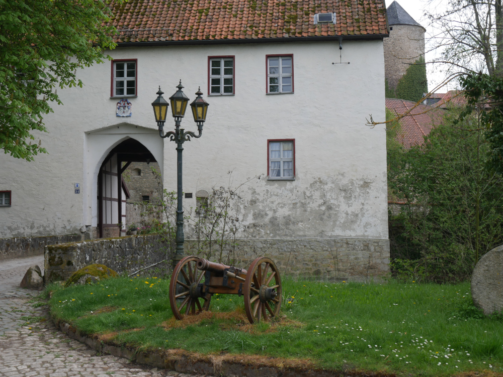 Das Foto zeigt einen Teil des Torhauses der Westerburg, davor eine alte Kanone und hinten ist der Burgturm erkennbar.