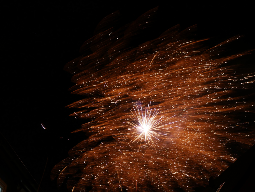 Das Foto zeigt die Explosion von Feuerwerksraketen am Himmel. Es sind viele Kleine Leuchtpunkte und Fäden dabei, was dem ganzen ein wenig den Eindruck eines astronomischen Bildes einer fernen Galaxis gibt.