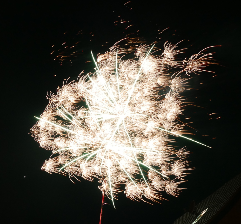 Das Foto zeigt die Expolsion von Feuerwerksraketen am Himmel. Man sieht die beiden Sternförmigen Hauptexplosionen und dann viele kleinere Explosionen.
