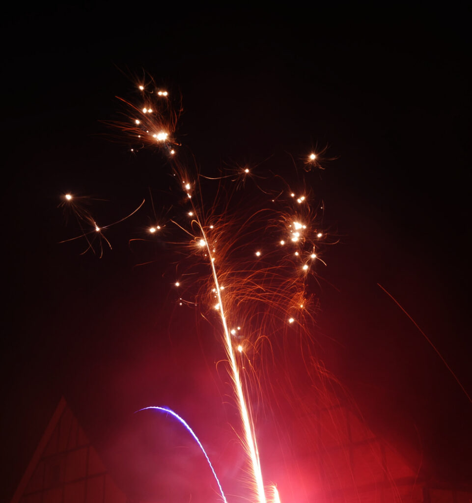 Das Foto zeigt Feuerwerk: Rote Explosionen in Richtung Himmel.