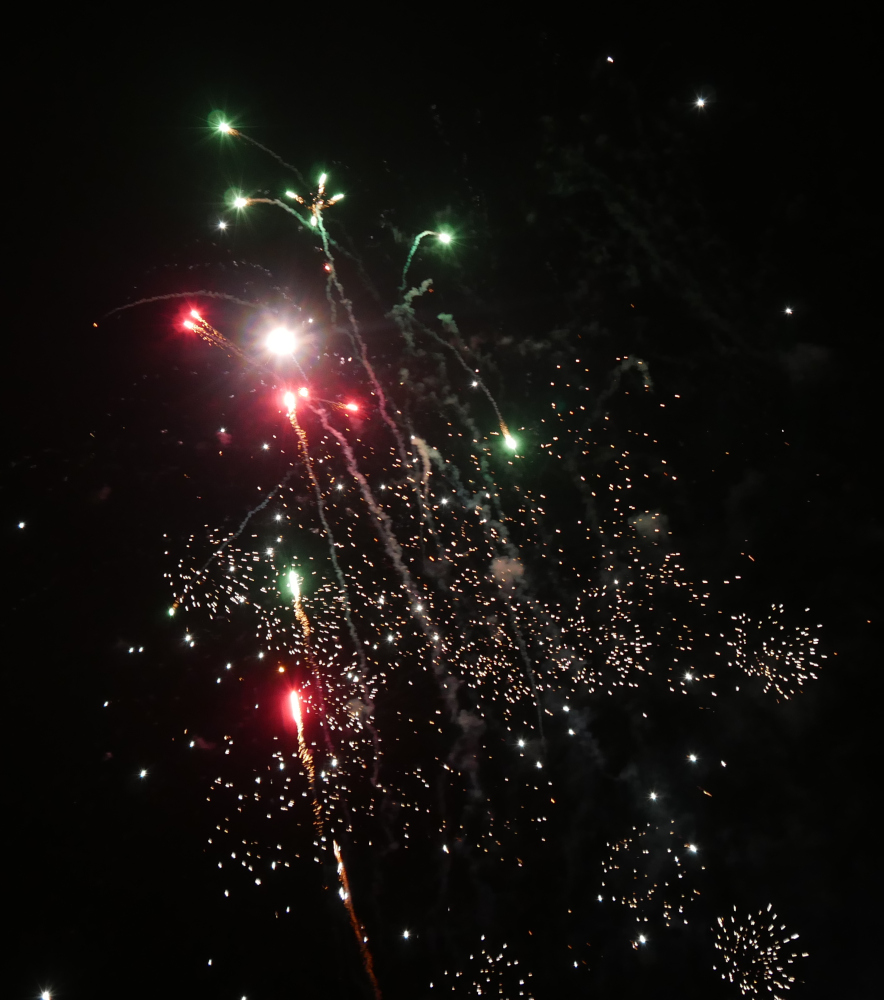 Das Foto zeigt buntes Feuerwerk, vor allem in rot und grün, am Nachthimmel.